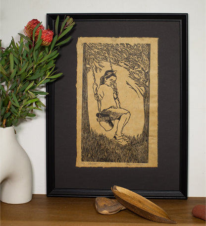 The Alicia linocut in a black frame, beside a vase of native foliage