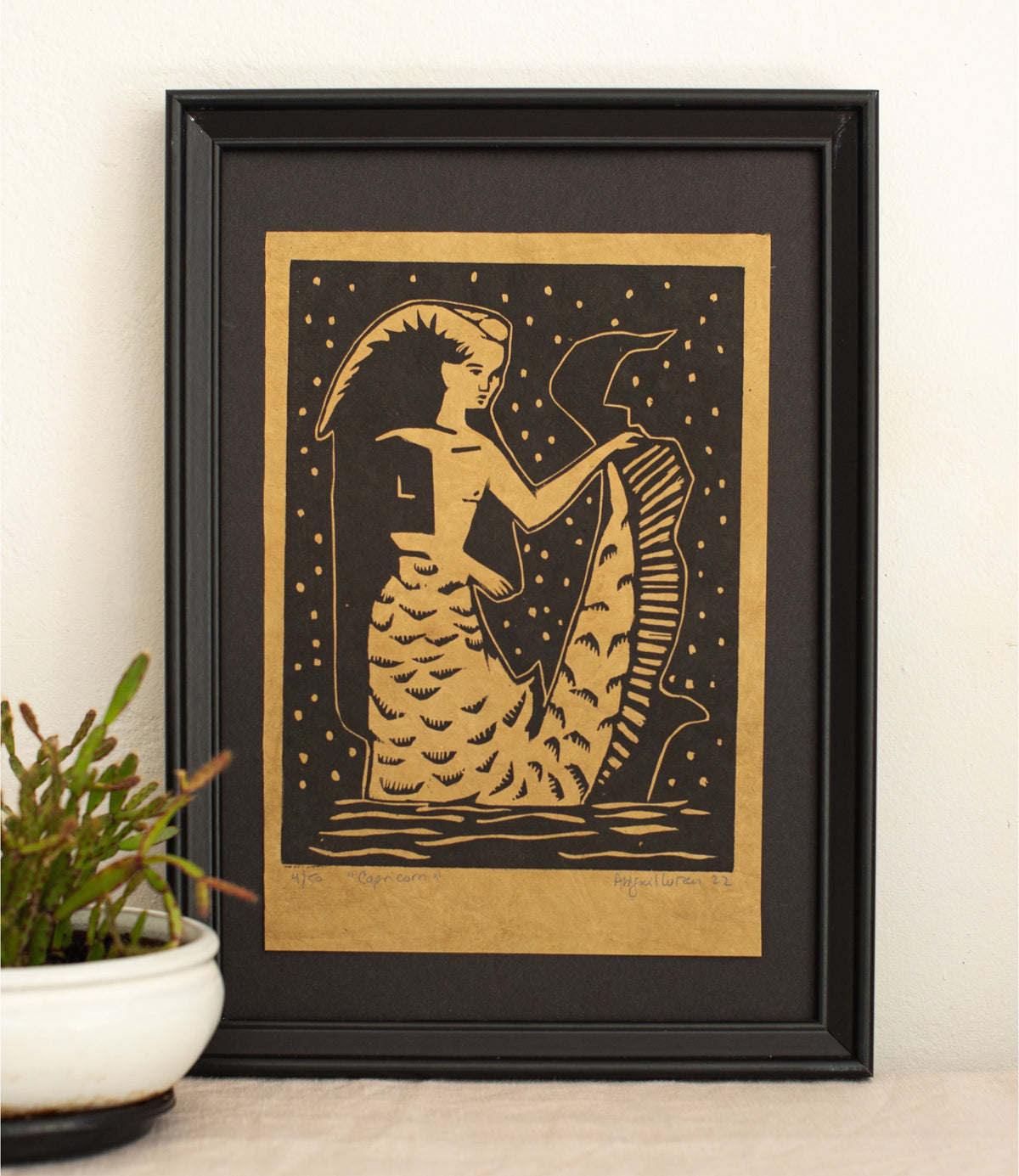 The Capricorn woodcut in a black frame, printed in gold and black