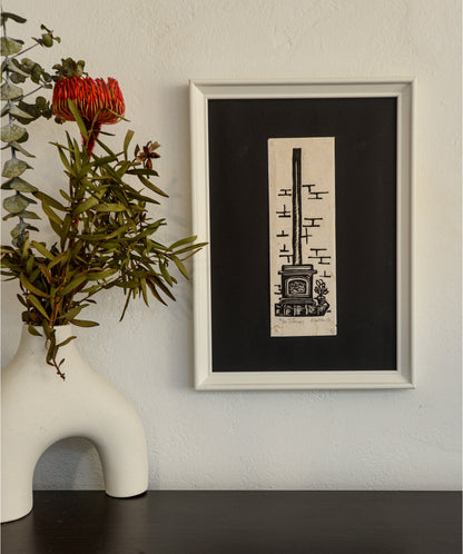 The Interiors linocut in a black frame, beside a vase of native foliage
