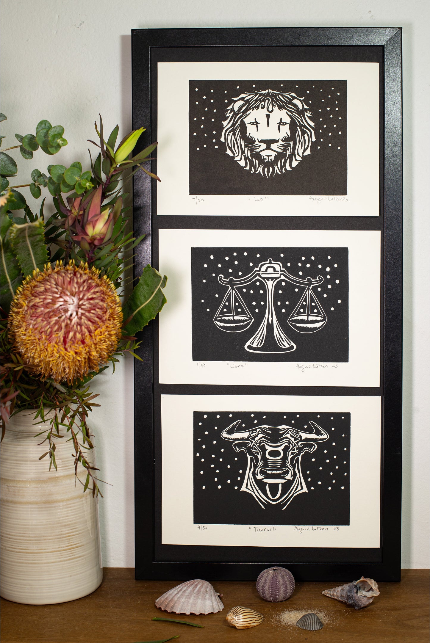 Three framed zodiac linocuts displayed together on a shelf
