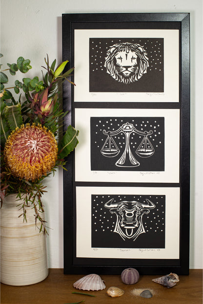 Three framed zodiac linocuts displayed together on a shelf