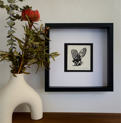 The Rose, The Fly linocut in a black frame beside a vase of native flowers