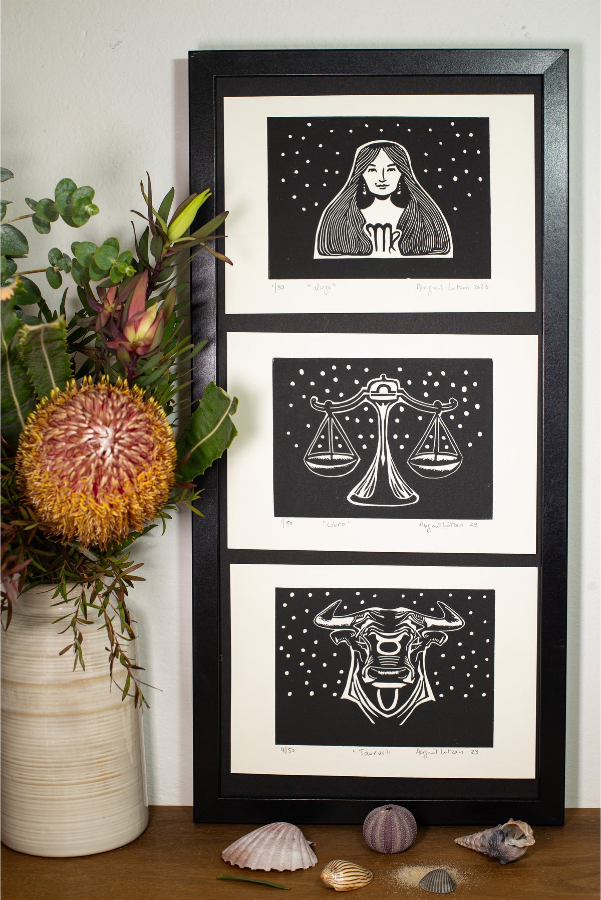 The Taurus linocut in a black frame, beside a vase of native flowers